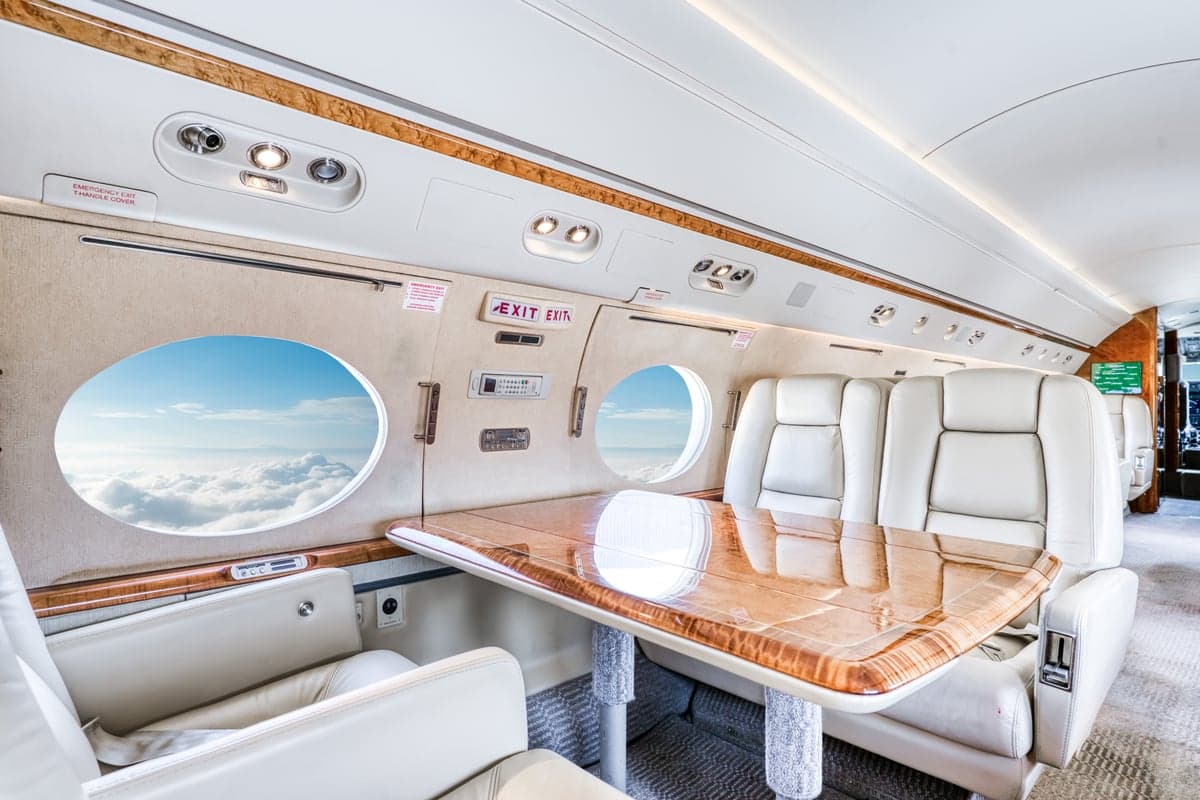 A view of the aircraft's interior cabin with a table and leather seats.