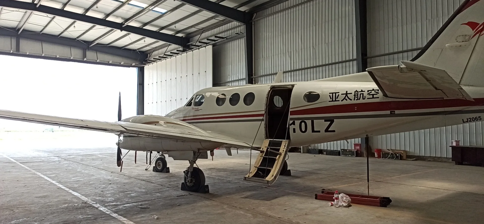 A King Air B-10LZ aircraft is parked inside a hangar with the door open.