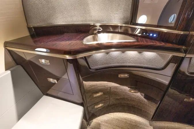 Aircraft lavatory mirror and vanity with dark wood trim.