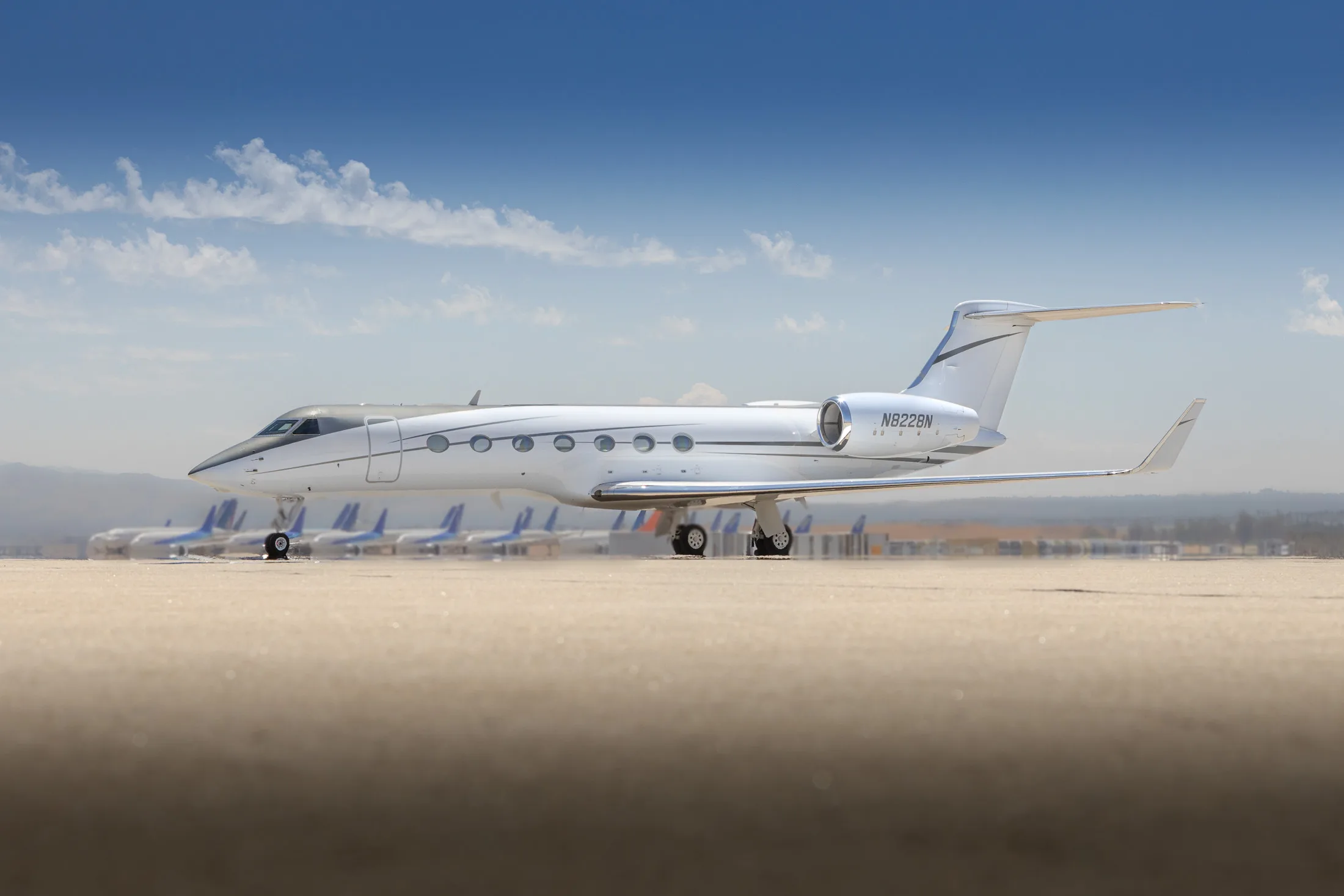 A Gulfstream aircraft is parked on the tarmac with other aircraft in the background.