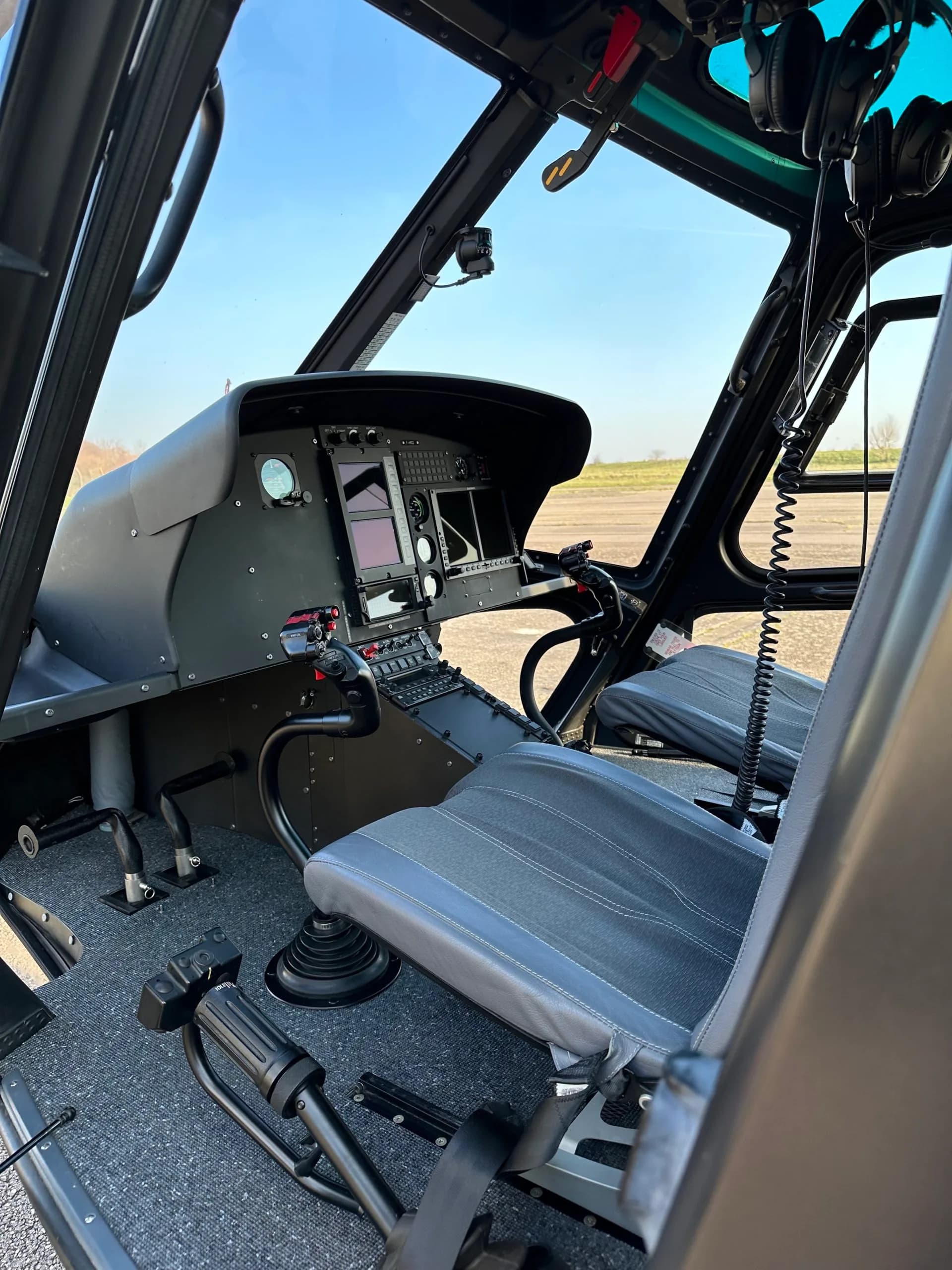 View of the helicopter cockpit with seats and instrument panel.