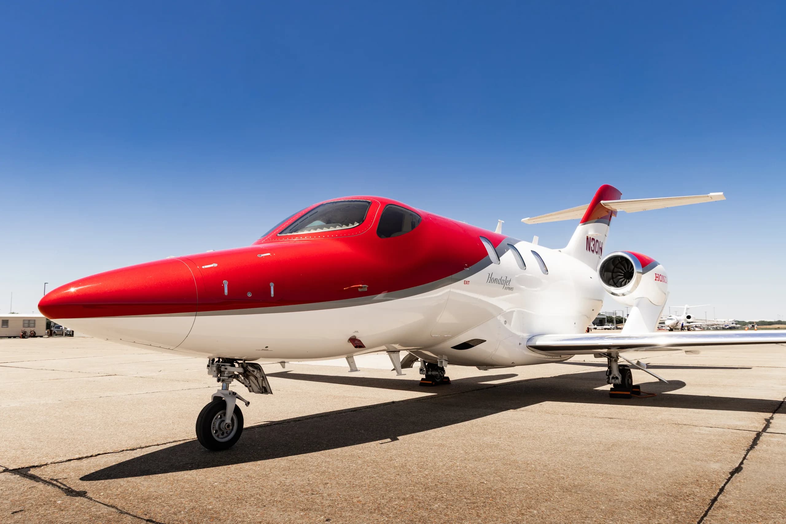 A white and red HondaJet HA-420 (N30HJ) parked on a tarmac, viewed from the front-left.