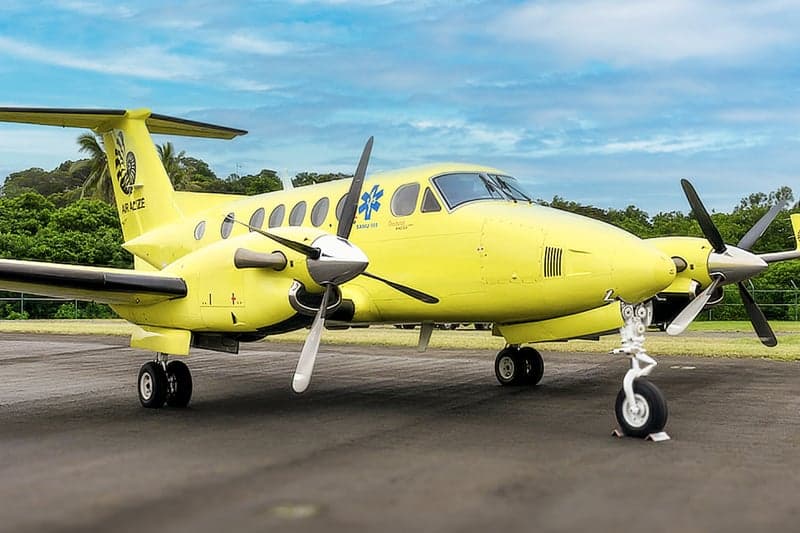 A yellow King Air on the tarmac with its landing gear visible.