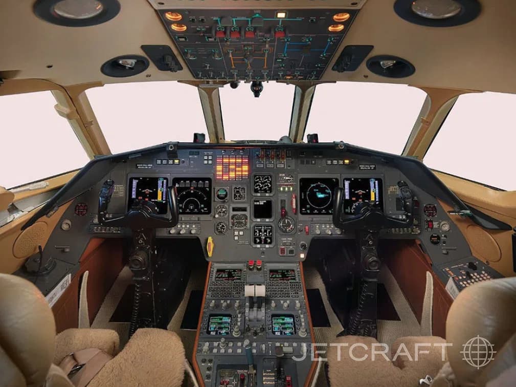 The cockpit of a business jet with multiple display screens and control panels.