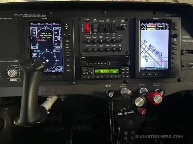 A close-up of the aircraft's instrument panel, featuring two large Garmin displays and various switches and controls.