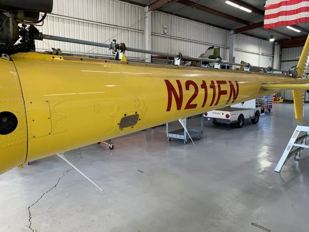 A close-up view of the yellow tail boom of the Eurocopter AS350 B3 helicopter, N211FN, showing the red registration.