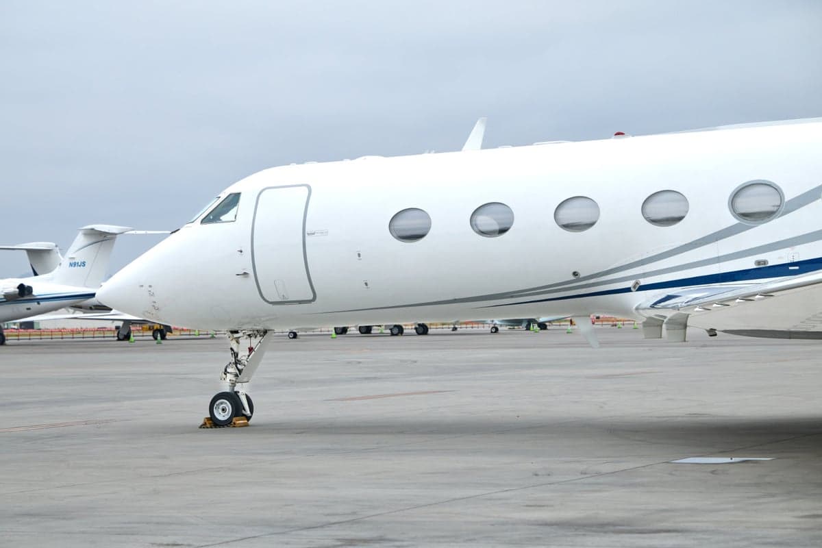 A white Gulfstream G450 aircraft is parked on the tarmac at night.