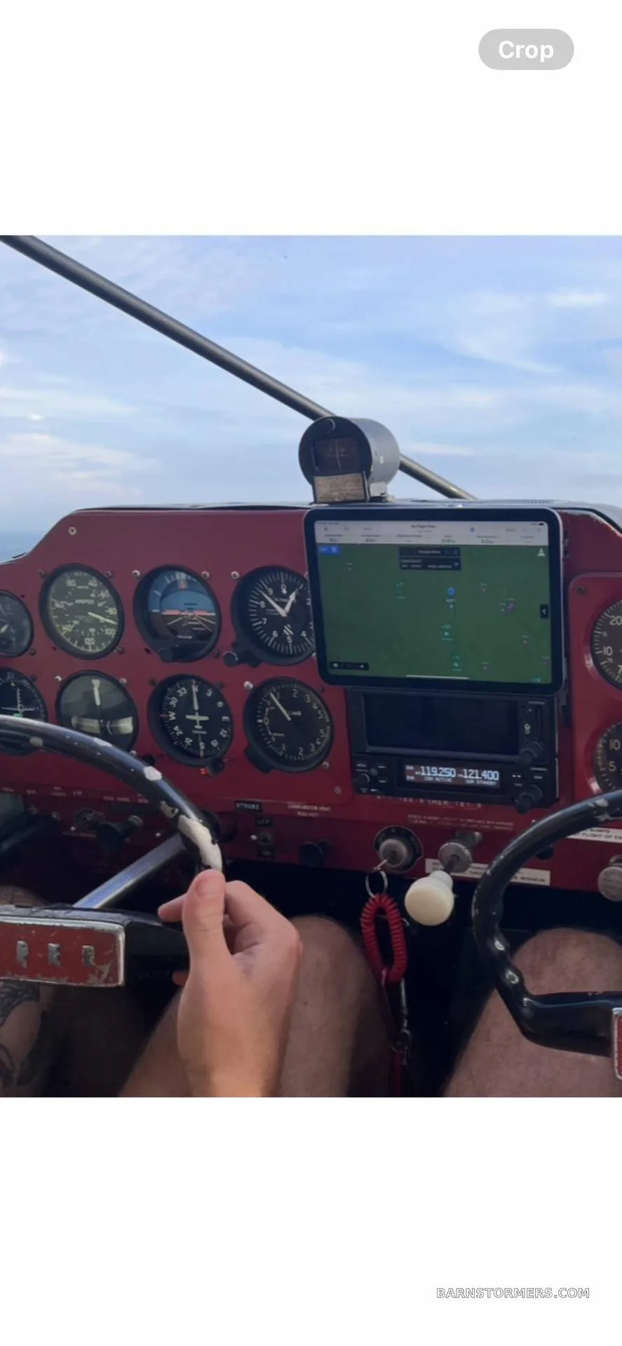 A pilot's view of a red aircraft instrument panel with an iPad mounted for navigation.