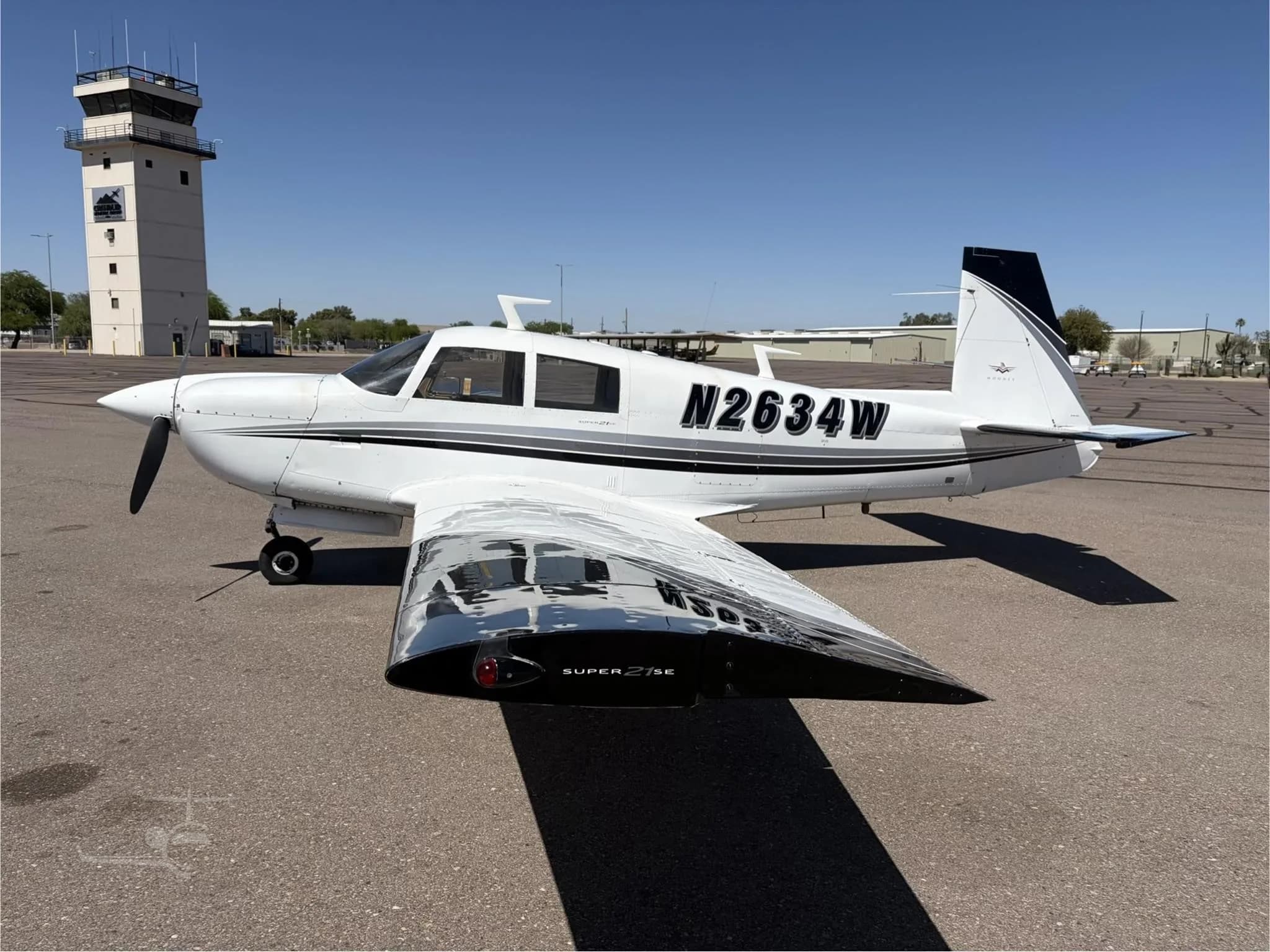 Mooney M20J Super 21SE aircraft N2634W parked on the tarmac with a control tower in the background.