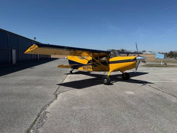 A yellow and blue Maule M-7-235 aircraft with registration N899Z parked on the tarmac.