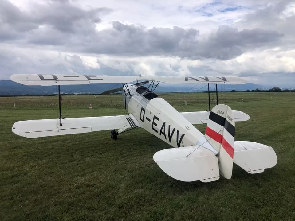 D-EAVV biplane parked on a grassy airfield, rear view.