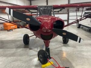 Front view of a red Cubcrafters aircraft with a black propeller.