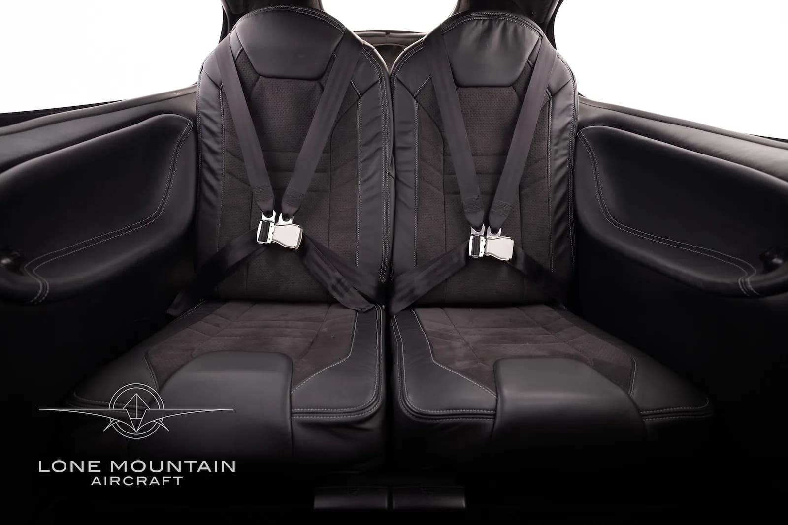 The black leather rear cabin seats of the Cirrus SR22 aircraft, showing two seats with seatbelts.