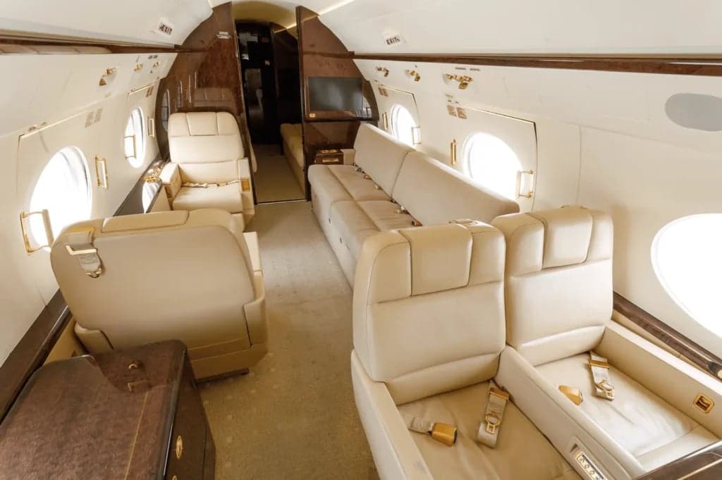 Interior view of the aircraft cabin with beige leather seats and wood trim.