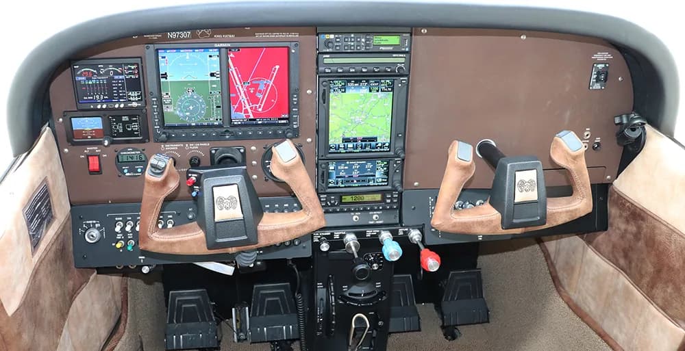 The cockpit of an aircraft, featuring a modern instrument panel with multiple digital displays and two yokes.