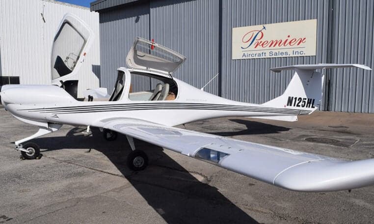 Diamond DA40 aircraft with registration N125HL parked in front of a hangar with its gull-wing doors open.
