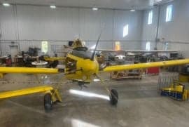 Front view of a yellow agricultural aircraft inside a hangar.