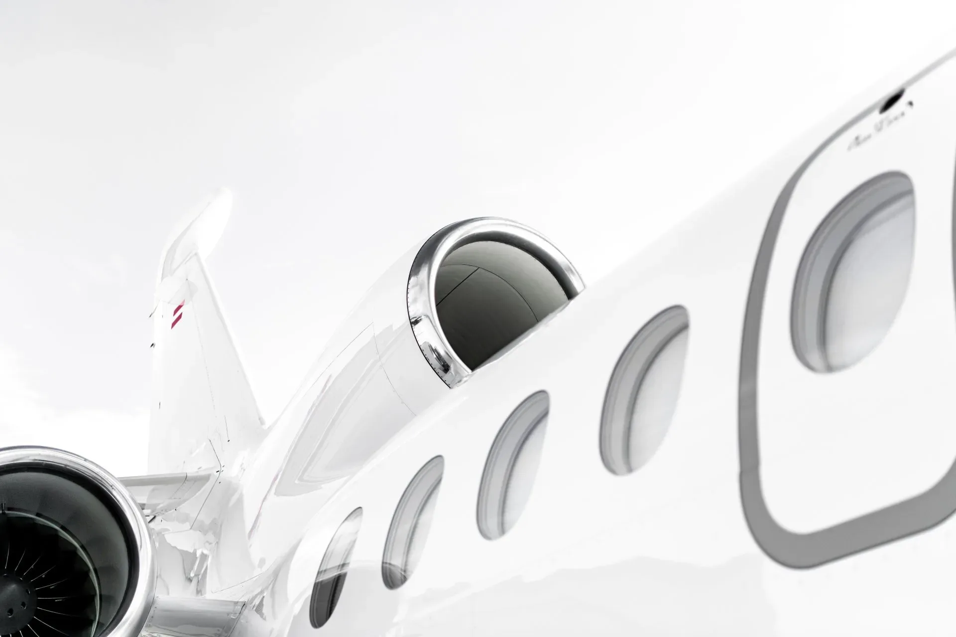 A close-up view of the tail, engine, and passenger windows of a white business jet.