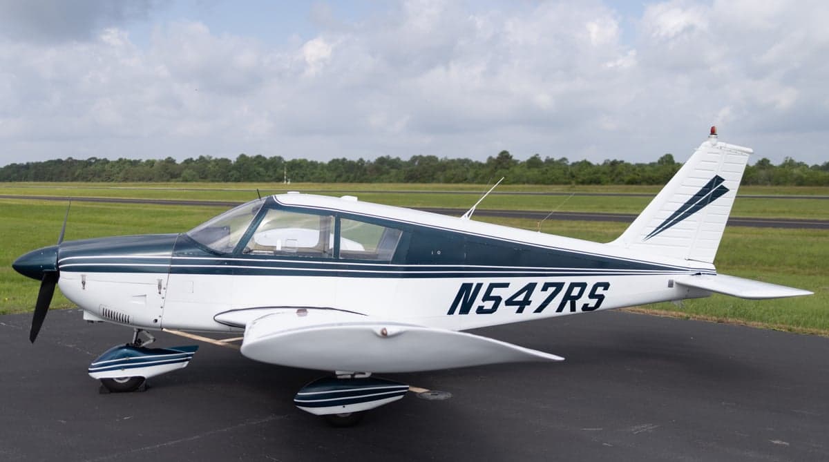 Side view of a white and blue aircraft with tail number N547RS on the tarmac.