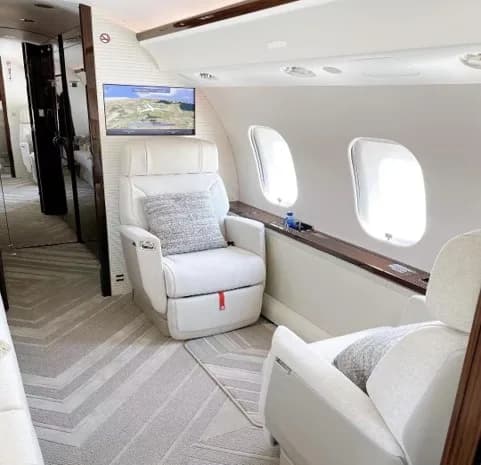 View of the aircraft interior with white leather seats and a small table.