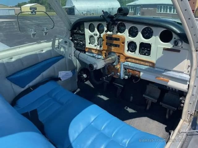 The cockpit of a small aircraft with a white and woodgrain instrument panel and blue seats.