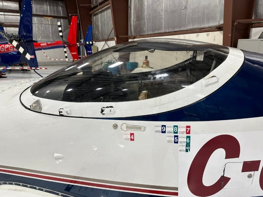 Close-up of the canopy and fuselage of a Questair Venture aircraft with registration C-GOER inside a hangar.