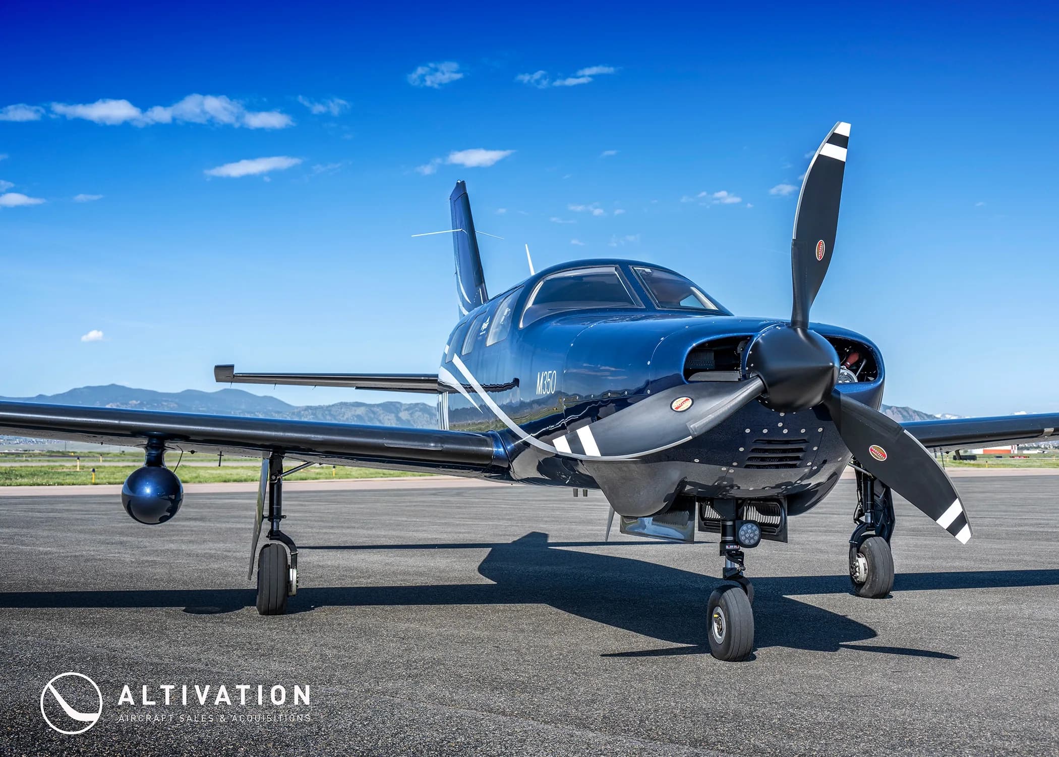 A front-quarter view of the dark blue Piper M350, tail number N115DW, parked on a tarmac.