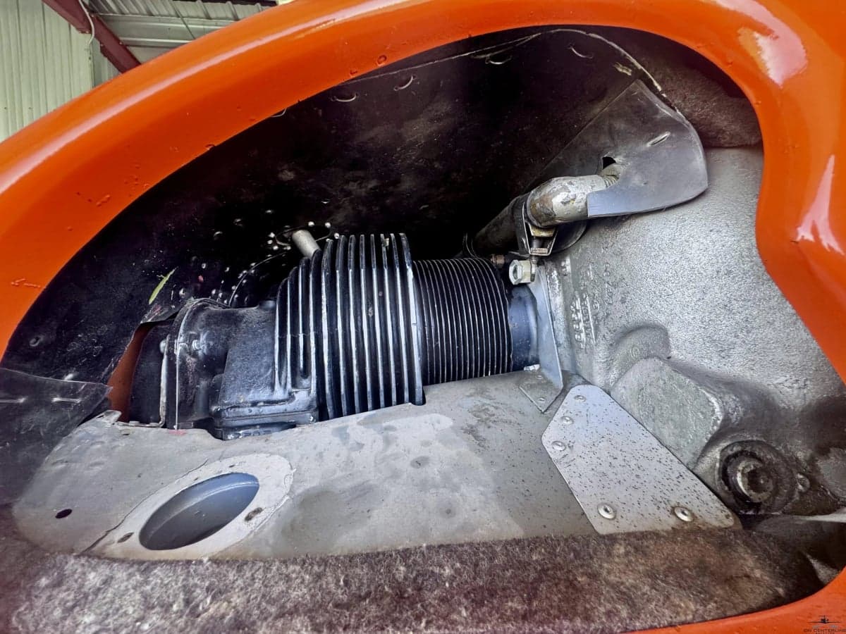 A close-up view of the engine cylinders inside the orange aircraft's cowling.