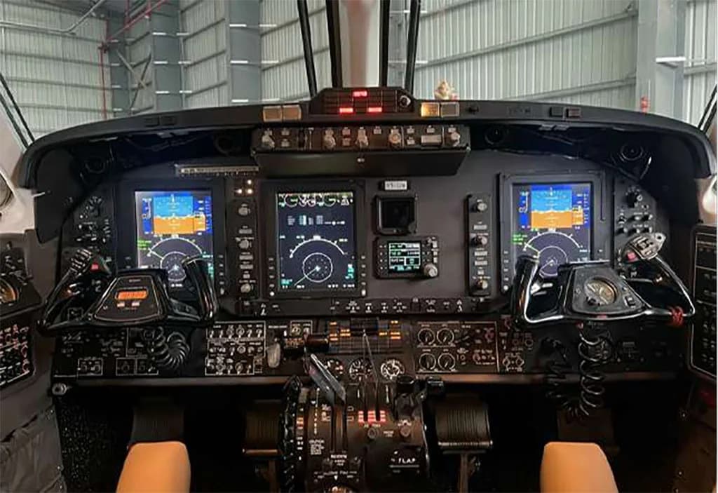 The cockpit of a modern turboprop aircraft, featuring multiple digital displays and control yokes.