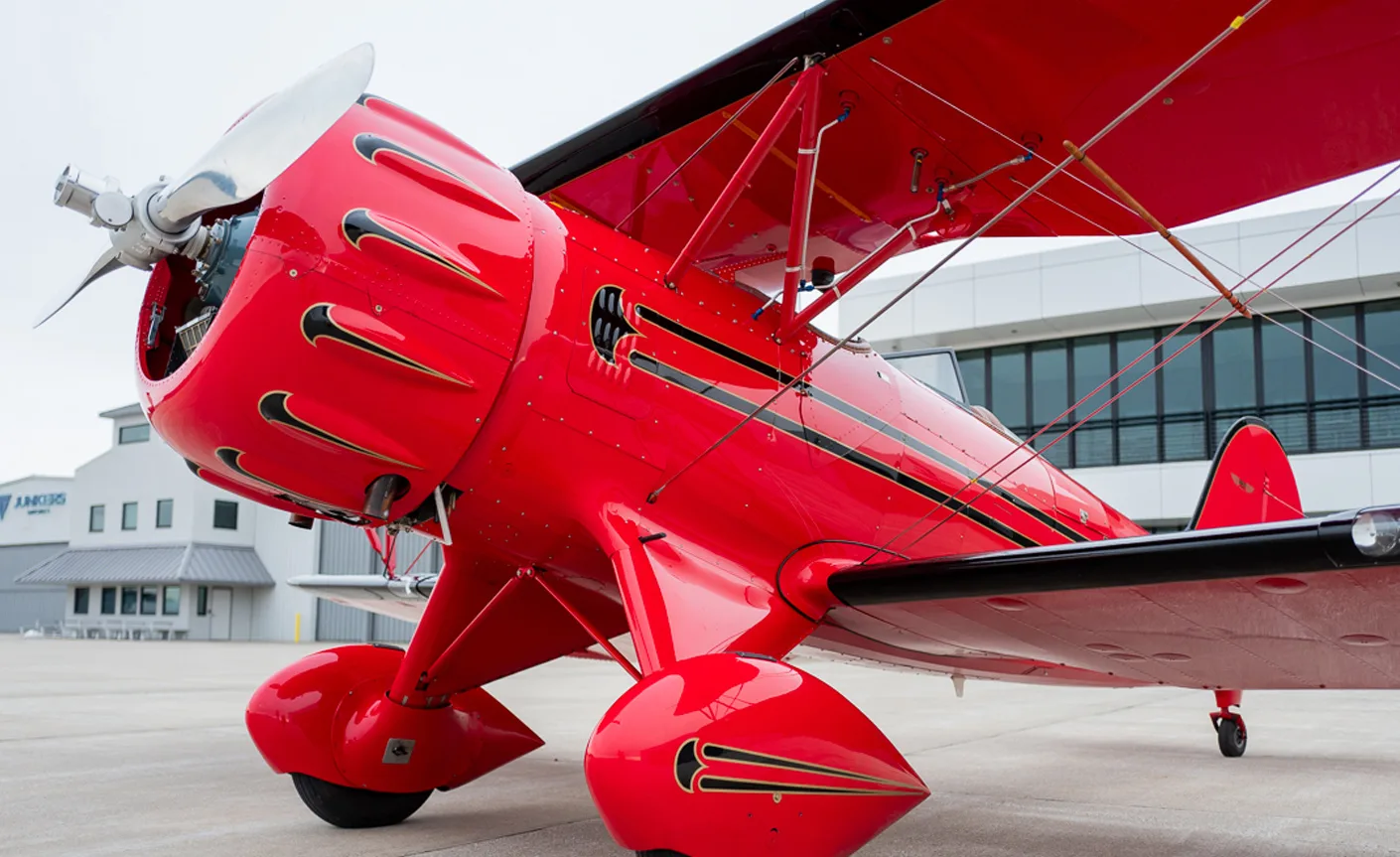 Close up of the front of a red biplane with a silver propeller.