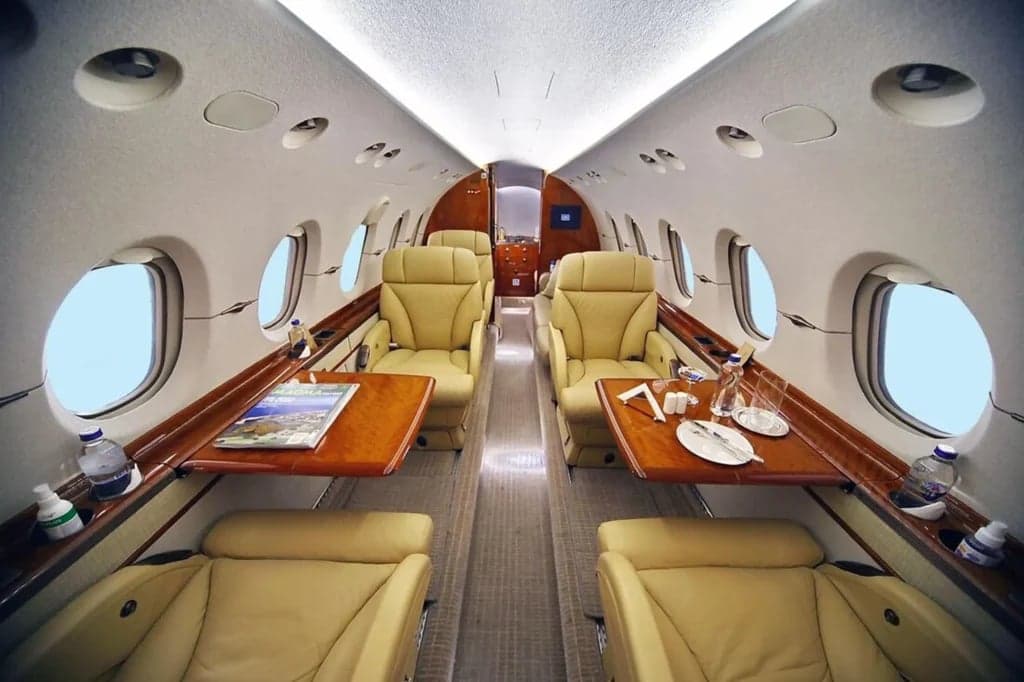 A view of the aircraft's interior with tan leather seats and wooden tables.