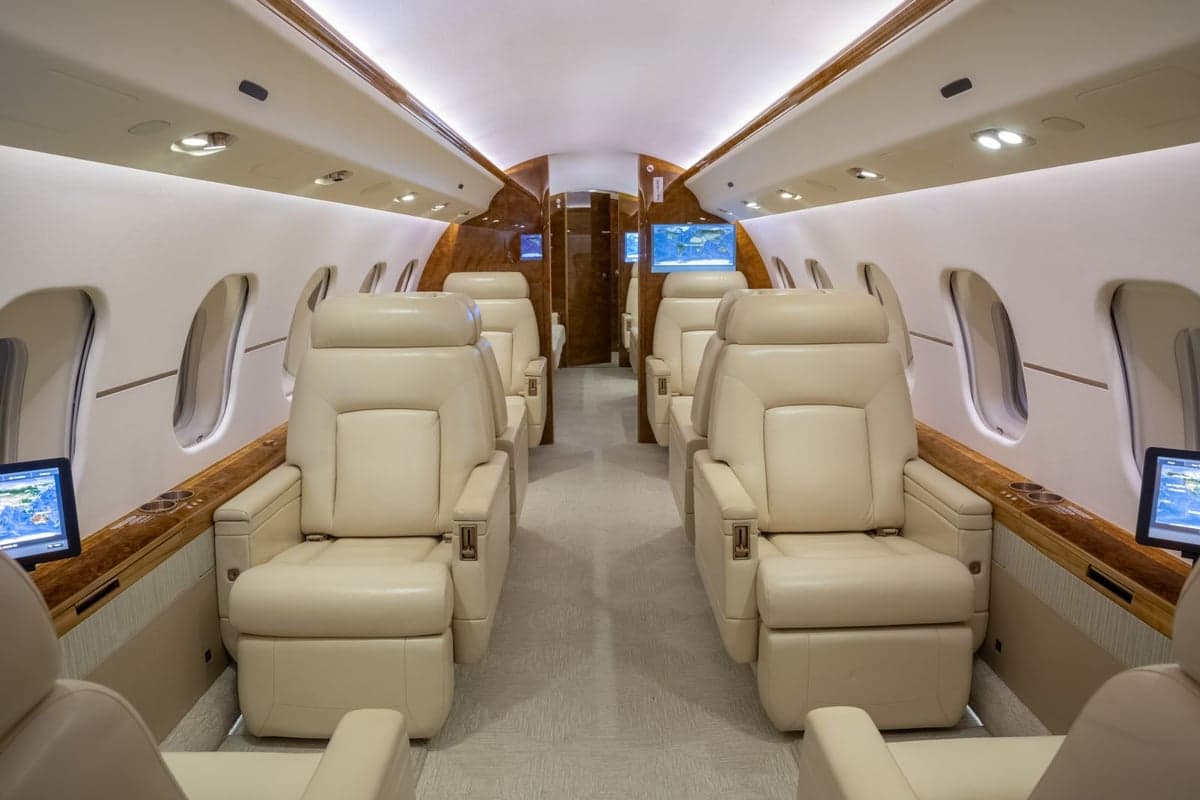 A view of the aircraft's interior with cream-colored leather seats and wood trim.