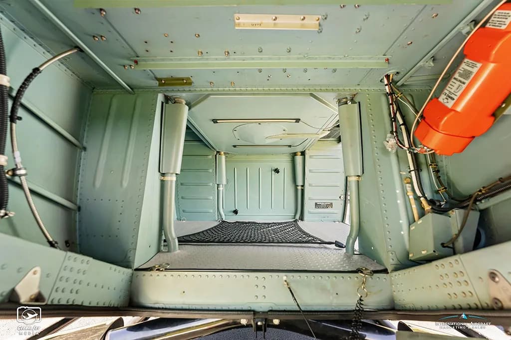 Interior view of an empty helicopter cargo compartment with a black net.