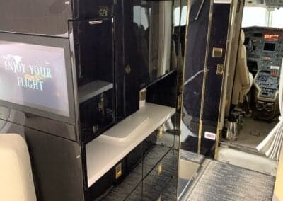 Interior view of the aircraft with a TV screen and cabinetry.