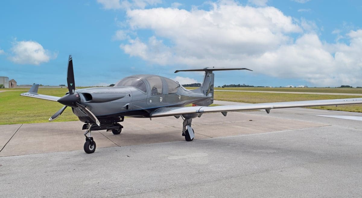 A gray Diamond DA50 RG aircraft, registration N59RG, with blue accents, parked on an airfield.
