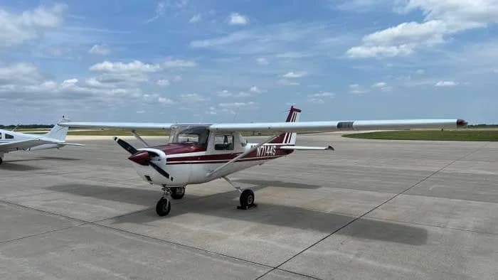 A Cessna 172 Skyhawk with a red and white paint scheme parked on a ramp.