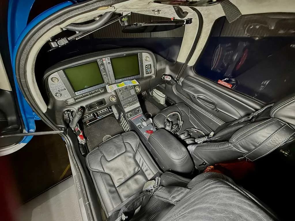 An overhead view of the modern glass cockpit of a Cirrus SR22T aircraft with black leather seats.