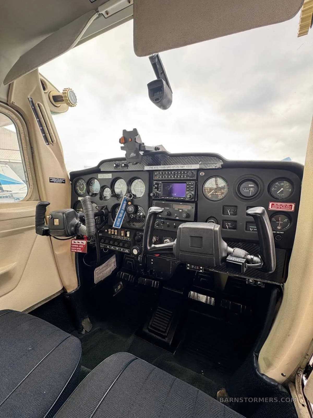 The cockpit of a small aircraft, showing the instrument panel, yokes, and controls from a slightly angled view.
