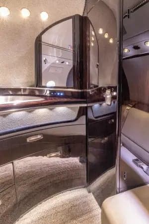 Aircraft cabin interior with leather seats and dark wood trim.