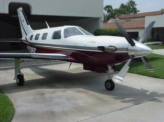 A maroon and white aircraft, N5326C, parked on a driveway.