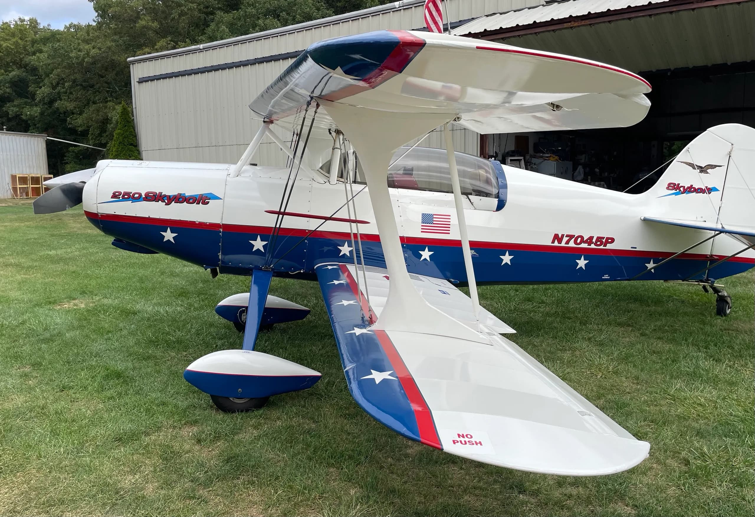 A three-quarter front-left view of the Acro Sport II Skybolt biplane, highlighting its biplane wings and patriotic paint scheme.