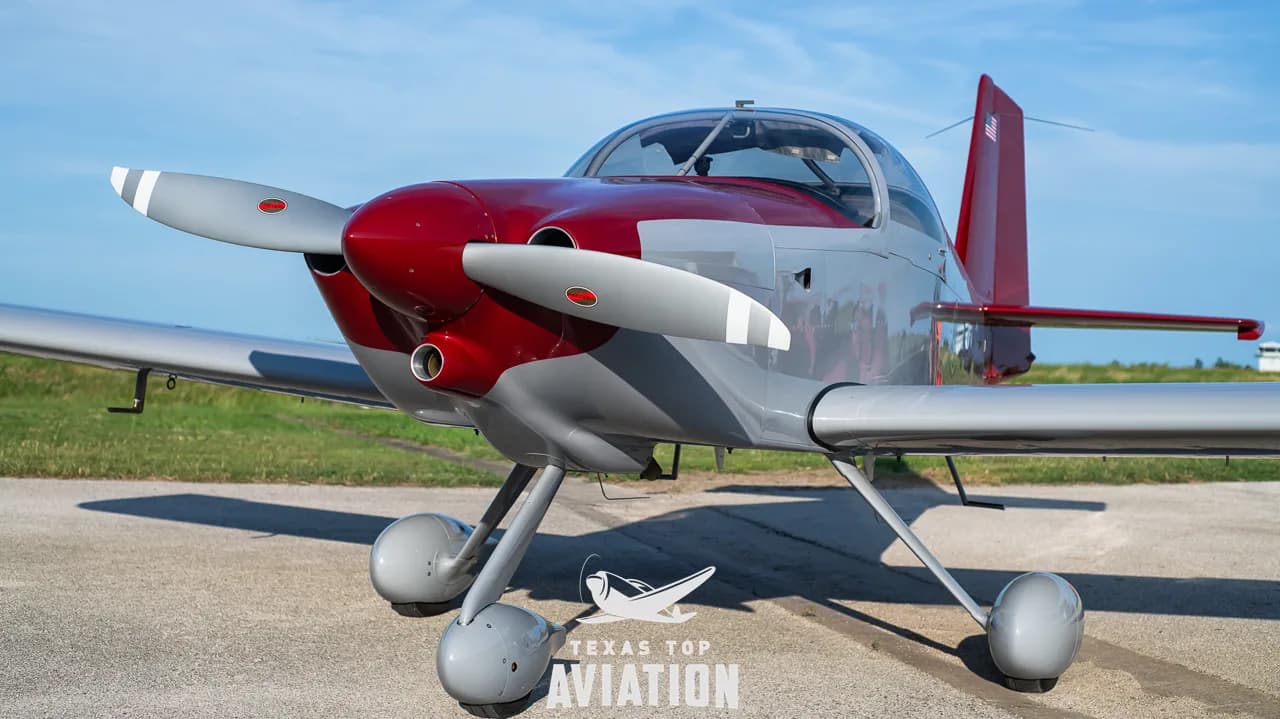 A close-up front view of the gray and red single-engine aircraft, N1359L, showing its propeller and landing gear.