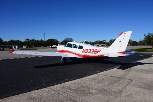 A white and red painted aircraft, N9338P, is parked on the tarmac at an airport.