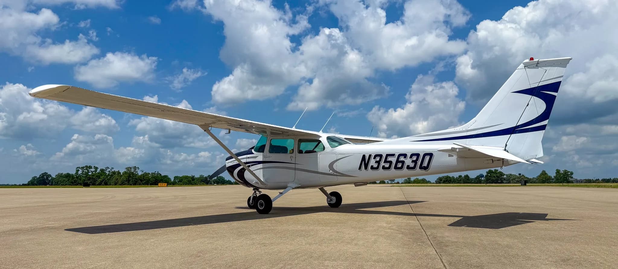 Right side view of a white and blue Cessna 172 with registration N3563Q on an airfield.