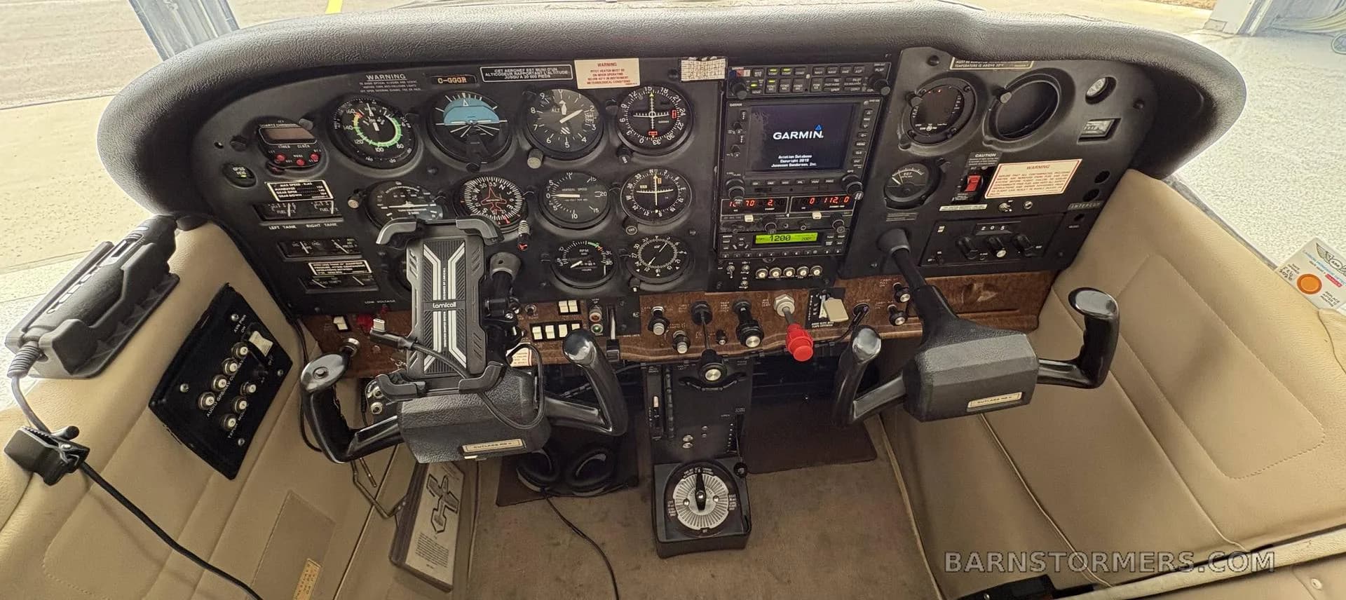 The instrument panel of a small aircraft, featuring analog gauges and a Garmin GPS unit.