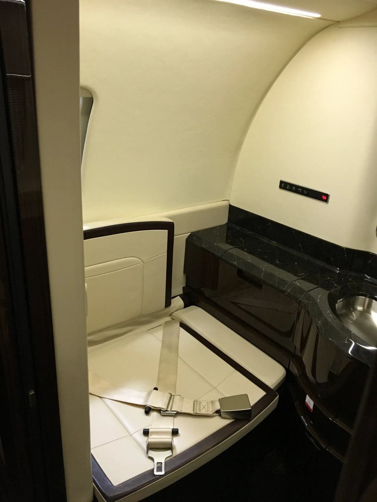 A lavatory seat with seatbelts inside the aircraft.