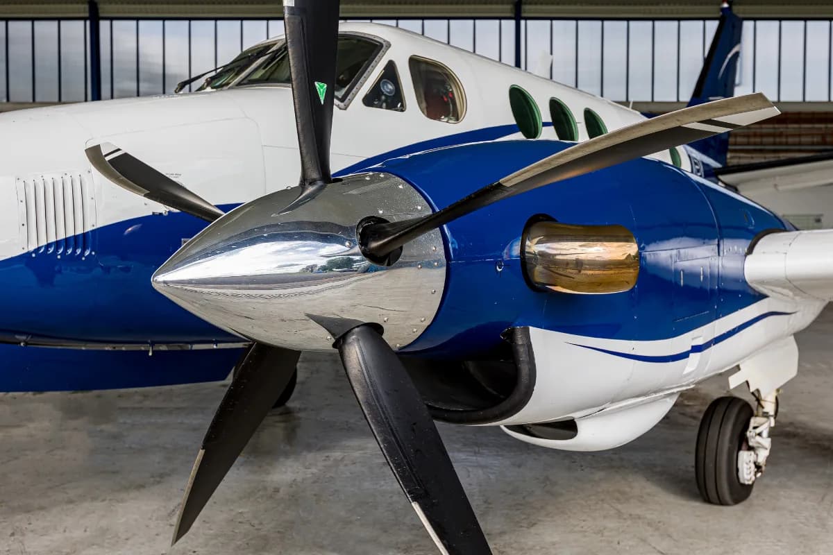 Close-up view of the polished propeller and engine cowling of a white and blue Beechcraft King Air C90.