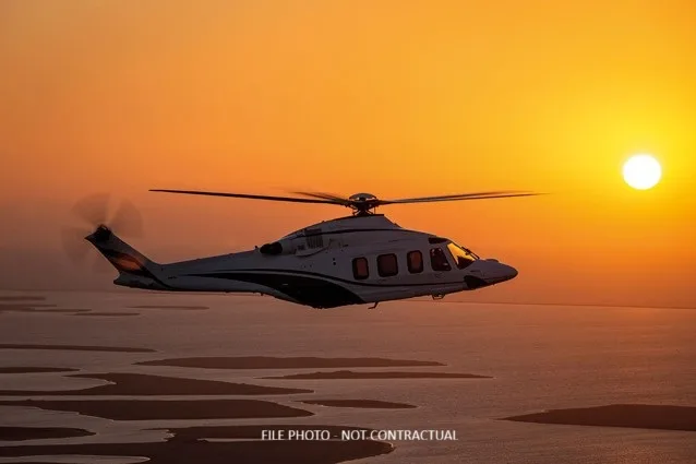 Generic helicopter flying over the ocean at sunset.