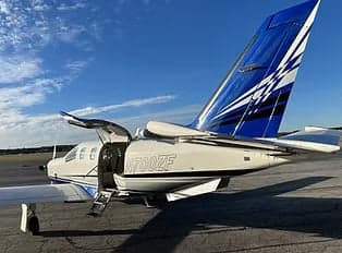 Rear view of the TBM 900 aircraft with the door open and tail visible.