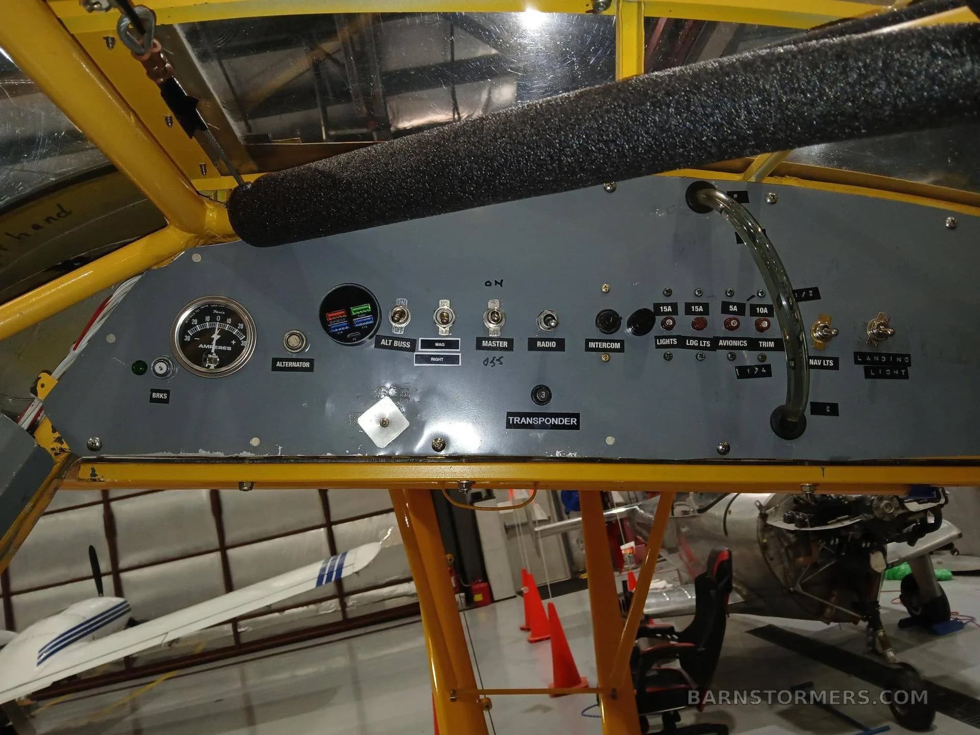 The grey overhead or side panel of an aircraft cockpit, displaying switches, circuit breakers, and a transponder.
